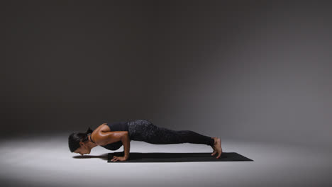 Foto-De-Estudio-De-Una-Mujer-Madura-Vistiendo-Ropa-De-Gimnasio-De-Pie-Sobre-Una-Alfombra-Haciendo-Una-Variedad-De-Ejercicios-De-Estiramiento-De-Pilates